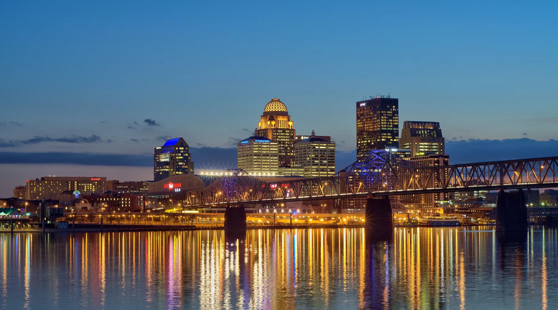 Dusk skyline photo of the Louisville waterfront with light reflections in the Ohio River