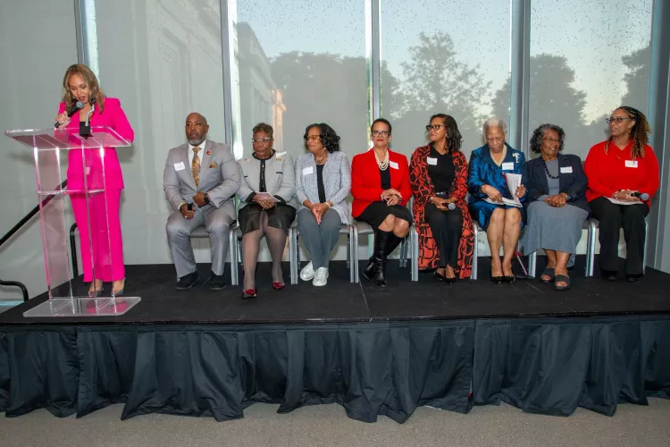 A person speaks at a podium while others listen.