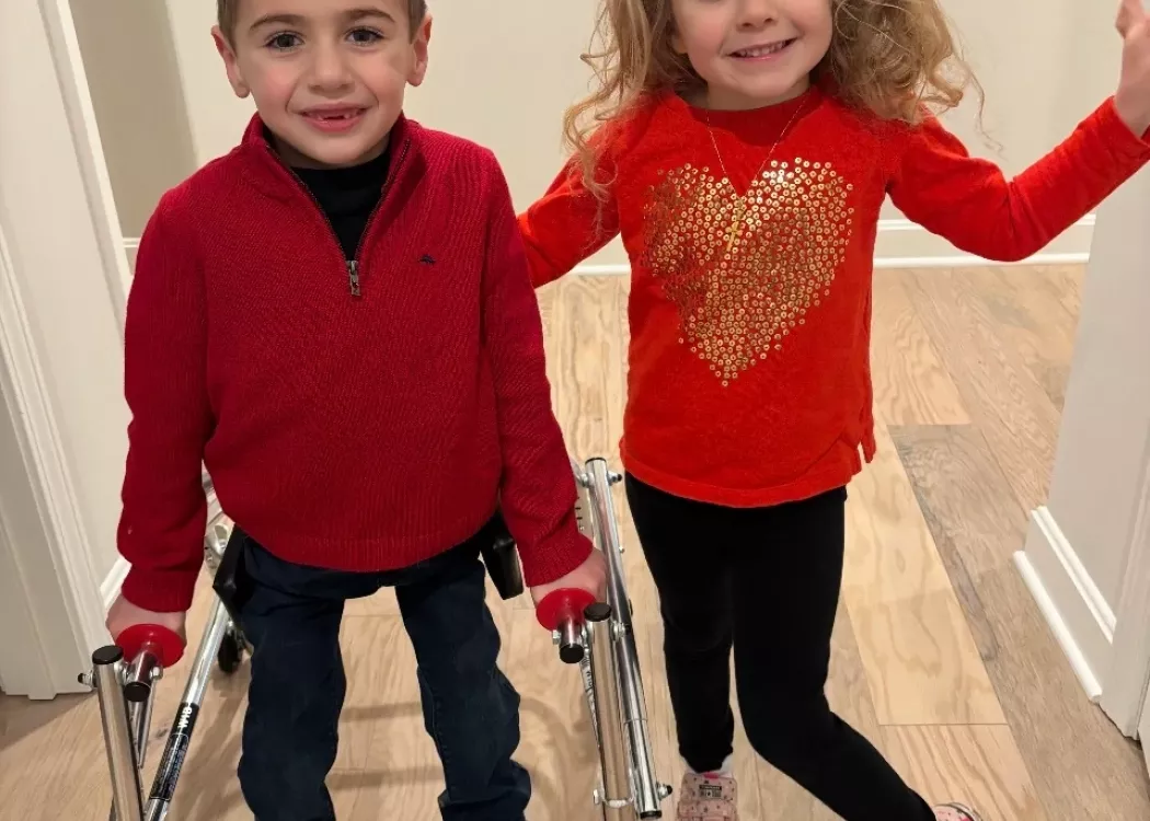 Two children dressed in red standing in a hallway
