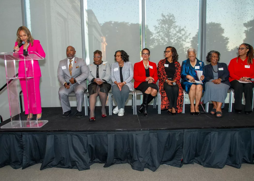 A person speaks at a podium while others listen.