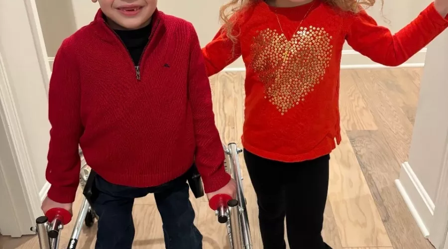 Two children dressed in red standing in a hallway